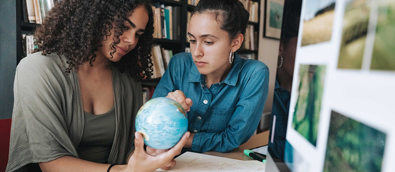 Two female students examining a globe